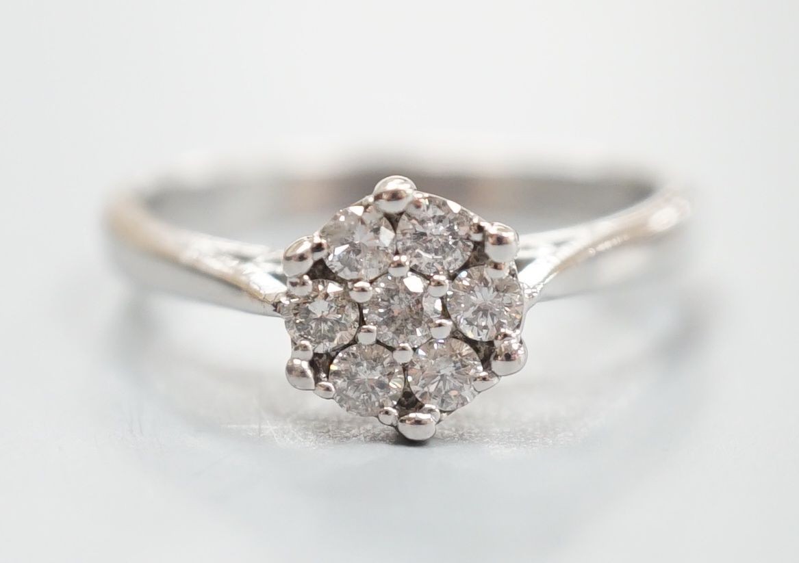 A modern 18ct white gold and seven stone diamond set flower head cluster ring, size O/P, gross weight 4 grams